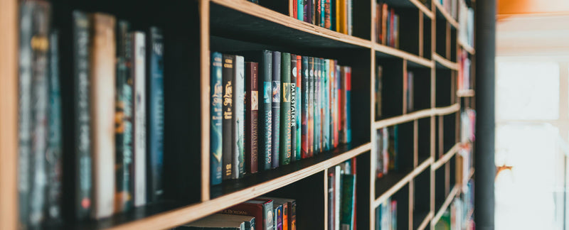 Bookshelf filled with books in a room with wooden beams.